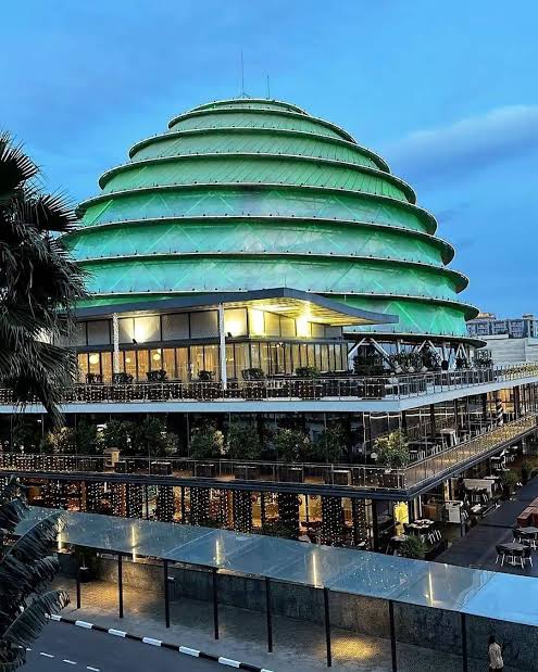 The illuminated green dome of the Kigali Convention Centre at dusk, above tiered glazed terraces